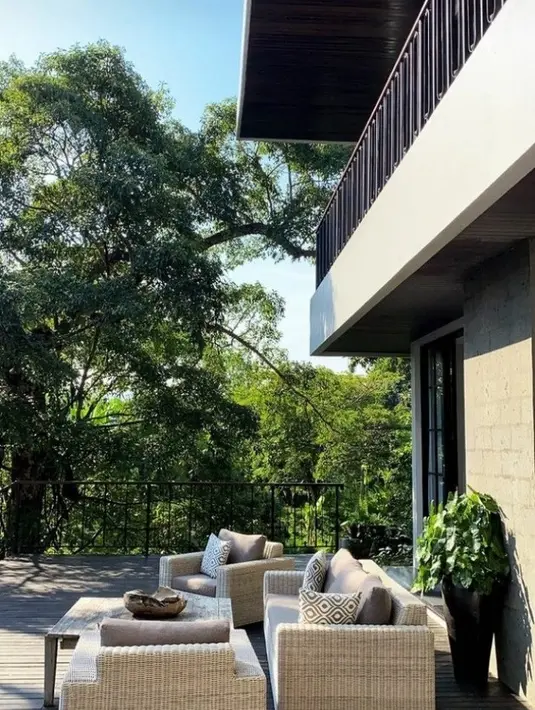 Halaman yang luas jadi salah satu spot menarik di luar rumah. Bagian ini didekorasi apik dengan kursi-kursi rotan dengan tema earthy tone. (Instagram @andrew.white_)