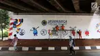Pejalan kaki melintasi mural Asian Games 2018 yang menghiasi kolong Jembatan Layang Tol Bintaro, Jakarta, Senin (13/8). Mural tersebut untuk sosialisasi dan mendukung Asian Games. (Liputan6.com/Fery Pradolo)