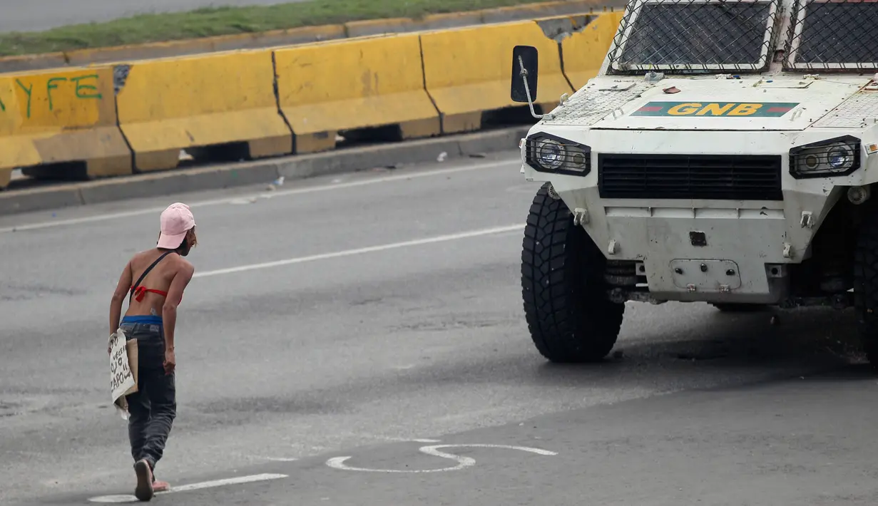 Demonstran anti-pemerintah menantang sebuah kendaraan lapis baja Garda Bolivarian Nasional selama bentrokan di sepanjang jalan raya di Caracas, Venezuela, (19/6). (AP Photo / Ariana Cubillos)