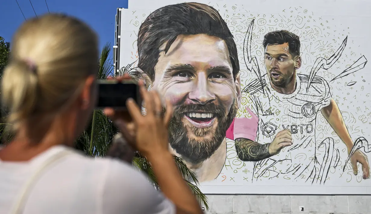 <p>Seorang wanita memotret mural besar bergambar Lionel Messi di Wynwood, Miami, 10 Juli 2023. La Pulga akan melakukan debutnya di Inter Miami pada 21 Juli di Piala Liga. (AFP/Chandan Khanna)</p>