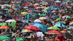 Kerumunan pengunjung berkumpul di pantai setelah masa pelonggaran pembatasan sosial akibat covid-19 di Bournemouth, Kamis (25/6/2020). Menurut ramalan cuaca, Inggris mengalami hari terpanas tahun ini dengan suhu yang diperkirakan akan meningkat lebih tinggi. (Andrew Matthews/PA via AP)