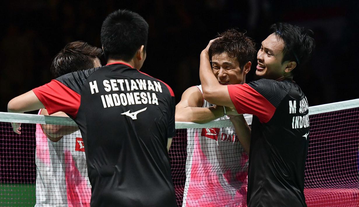 Pasangan Indonesia, Hendra Setiawan/Mohammad Ahsan memeluk wakil Jepang, Takuro Hoki/Yugo Kobayashi, usai menjuarai Kejuaraan Dunia Bulutangkis 2019 Minggu (25/8). Indonesia menang 25-23, 9-21, 21-15. (AFP/Fabrice Coffrini)