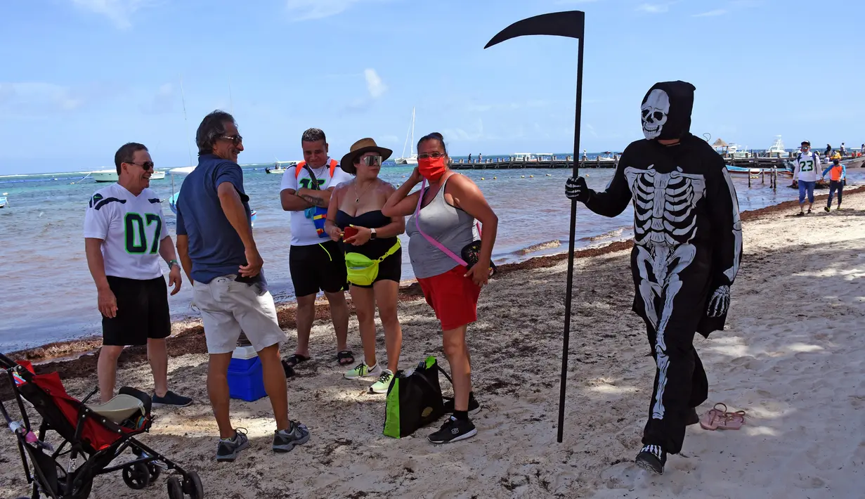 Seorang pria muda yang menyamar sebagai malaikat maut berkeliling pantai Puerto Morelos di Puerto Morelos, Quintana Roo, Meksiko, Sabtu (1/8/2020). Pria itu meminta wisatawan dan penduduk setempat kembali ke rumah karena pantai masih tertutup bagi pengunjung di tengah COVID -19. (ELIZABETH RUIZ/AFP)