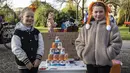 Anak-anak berpose di samping cangkir kertas sambil memajang gambar presiden Rusia Vladimir Putin yang dipajang di atas meja dalam acara perayaan Hari Raja di Vondelpark di Amsterdam, pada 27 April 2023. (Dingena Mol / ANP / AFP)