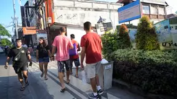 Turis mancanegara berjalan melewati papan izin mendirikan bangunan (biru) di bekas lokasi bom Bali Sari Club di Kuta, Bali, Jumat (26/4). Perdana Menteri Morrison kesal karena saat terjadi serangan Bom Bali pada 2002 di Sari Club, puluhan warga Australia tewas di tempat ini. (SONNY TUMBELAKA/AFP)
