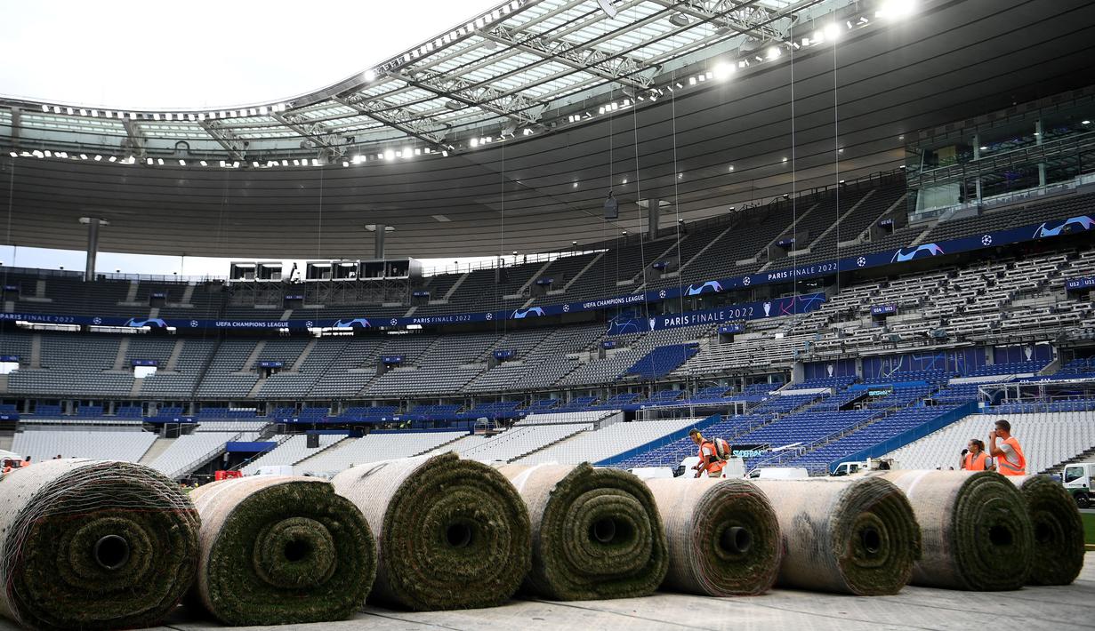 Sejumlah pekerja sedang memasang rumput hybrid baru di Stade de France, Saint-Denis, pada 24 Mei 2022 waktu setempat. Dalam waktu 48 jam, rumput baru yang ditanam di luar Barcelona, dipasang di Stade de France untuk pertandingan final Liga Champions antara Real Madrid dan Liverpool yang dijadwalkan berlangsung pada 28 Mei 2022. (AFP/Franck Fife)