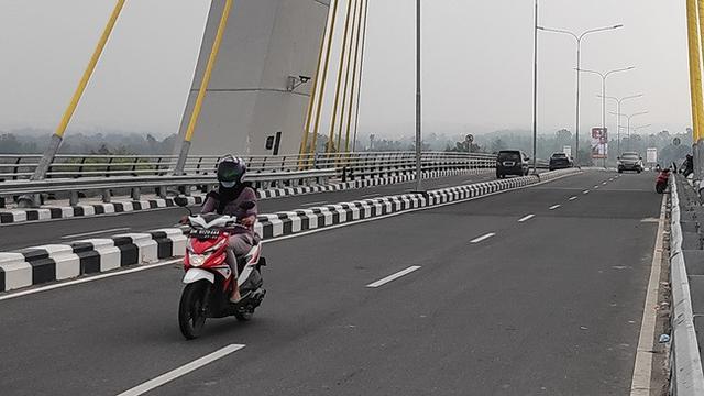 Pengendara sepeda motor di Pekanbaru memakai masker karena kabut asap dari kebakaran lahan.