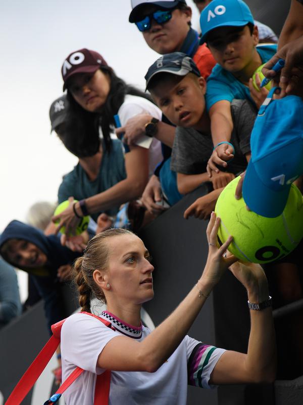 Petenis Republik Ceko, Petra Kvitova menandatangi bola yang disodorkan penggemarnya setelah mengalahkan Irina-Camelia Begu dari Rumania dalam babak kedua  turnamen Australia Terbuka di Melbourne, Rabu (16/1). (AP Photo/Andy Brownbill)