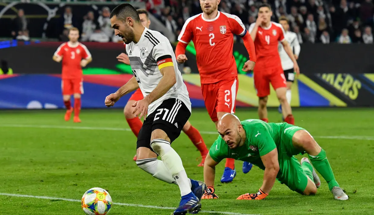 Gelandang Jerman, Ilkay Gundogan, berusaha melewati kiper Serbia, Marko Dmitrovic, pada laga persahabatan di Stadion Volkswagen, Rabu, (20/3). Jerman ditahan imbang 1-1 oleh Serbia. (AFP/John Macdugall)