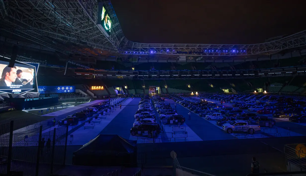 Orang-orang menonton film dari dalam mobil mereka di drive in yang dipasang di stadion sepak bola Palmeiras di Sao Paulo, Brasil, Kamis (25/6/2020). Stadion yang dapat menampung hingga 300 mobil tersebut berubah fungsi menjadi lokasi bioskop drive ini di masa pademi Covid-19. (AP Photo/Andre Penner)