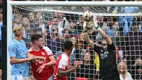 Kiper Arsenal, Aaron Ramsdale, berusaha menghalau bola saat melawan Manchester City pada laga Community Shield di Stadion Wembley, London, Minggu (6/8/2023). Arsenal mengalahkan Manchester City 4-1 lewat adu penalti setelah bermain imbang 1-1 selama 90 menit. (AFP/Glyn Kirk)