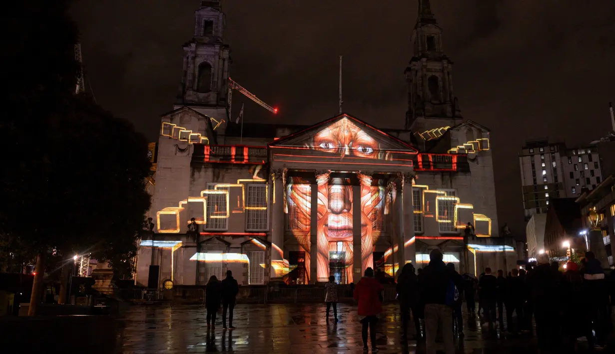 Masyarakat mengagumi instalasi seni bercahaya bertajuk 'Telekinetic Rumours' karya seniman Polandia Pani Pawlosky yang diproyeksikan di Balai Kota Leeds, utara Inggris, 10 Oktober 2019. Festival mengambil alih jalanan pusat kota Leeds selama dua malam di bulan Oktober. (Oli SCARFF/AFP)
