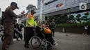 Petugas keamanan KAI Commuter Line membantu seorang calon penumpang lanjut usia (lansia) untuk masuk ke dalam Stasiun Sudirman, Jakarta, Selasa (10/12/2024). (Liputan6.com/Angga Yuniar)