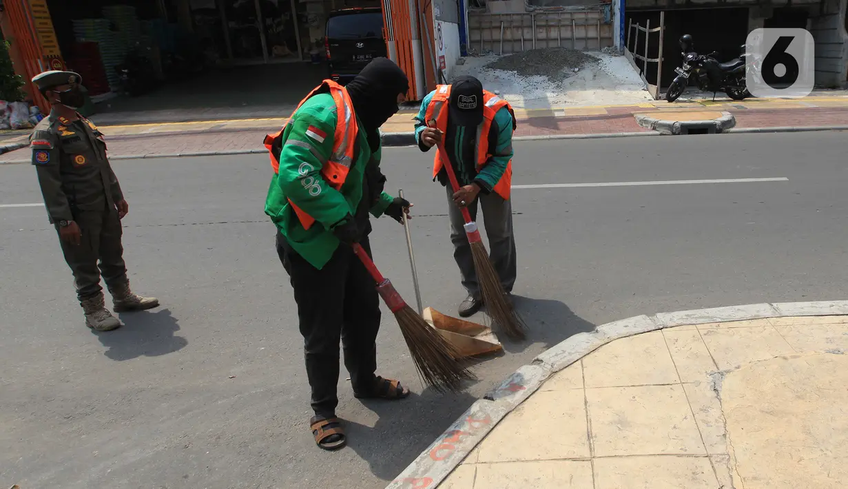 Warga yang terjaring razia masker mendapat hukuman menyapu jalan di kawasan Tanjung Duren, Jakarta, Kamis (19/11/2020). Satpol PP terus menindak warga yang melanggar protokol kesehatan selama PSBB transisi dengan sanksi kerja sosial di sarana umum atau membayar denda. (merdeka.com/Imam Buhori)