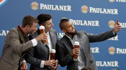 Pemain Bayern Thomas Mueller, Robert Lewandowski dan Arturo Vidal berselfie saat melakukan pemotretan sebuah perusahaan bir di Munich, Jerman, (13/9). (AP Photo / Matthias Schrader)