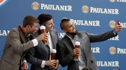 Pemain Bayern Thomas Mueller, Robert Lewandowski dan Arturo Vidal berselfie saat melakukan pemotretan sebuah perusahaan bir di Munich, Jerman, (13/9). (AP Photo / Matthias Schrader)