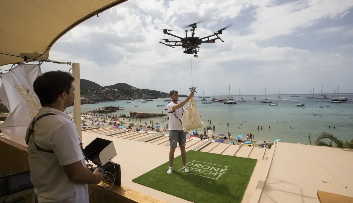 Pilot mengikat sekantong makanan ke drone dari Cala Tadira dekat Sant Josep de Sa Talaia di Pulau Ibiza, Spanyol, 24 Agustus 2021. Restoran Can Yucas dan perusahaan Galicia Aerocamaras meluncurkan layanan Drone to Yacht untuk mengirim makanan dan minuman eksklusif ke kapal pesiar. (JAIME REINA/AFP)