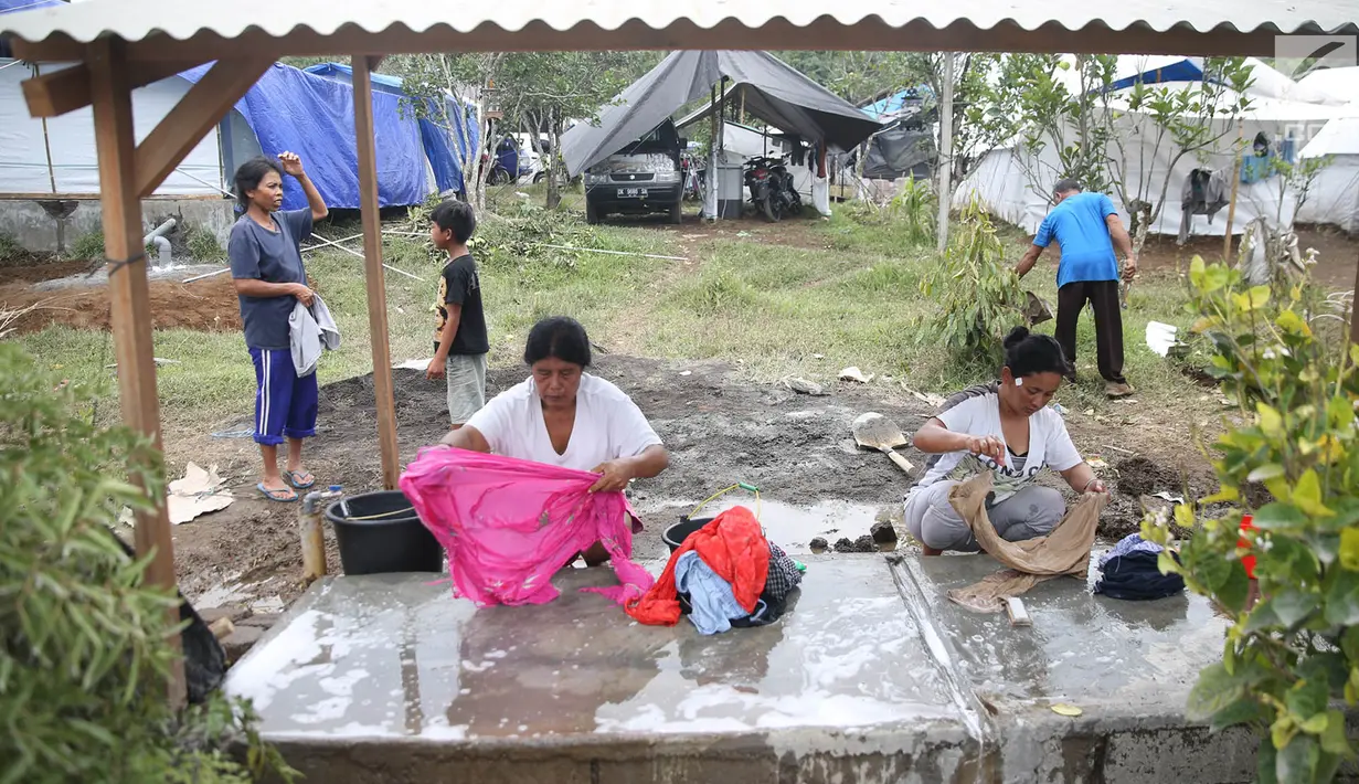 Warga pengungsi Gunung Agung mencuci pakaian di MCK sementara di Posko Pengungsi Rendang, Bali, Sabtu (2/12). Warga terpaksa memanfaatkan MCK seadanya yang berada di sekitar pengungsian. (Liputan6.com/Immanuel Antonius)