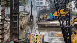 Pekerja menyelesaikan pemasangan dinding turap di kali pasar baru, Jakarta, Rabu (9/3/2022). Dinas Sumber Daya Air DKI Jakarta melakukan pemasangan turap bertujuan untuk mengantisipasi banjir serta tanah ambles di pinggir sungai. (Liputan6.com/Faizal Fanani)