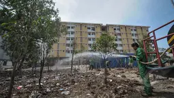 Petugas menyiram pohon di sekitar Rusun Muara Baru, Jakarta, Rabu (22/4/2015). Minimnya air bersih di rusun tersebut membuat kementerian pekerja umum menyediakan alat penyulingan air . (Liputan6.com/Faizal Fanani)