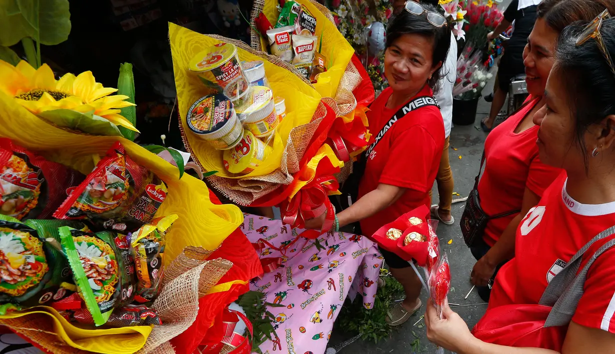 Sebuah toko bunga menjual buket snack dan bunga segar sehari sebelum Valentine Day di pasar bunga Manila, Filipina, Rabu (13/2). Sudah tradisi di seluruh dunia, setiap hari valentine identik dengan pemberian bunga atau coklat. (AP Photo/Bullit Marquez)