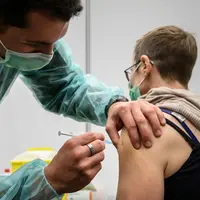 Tentara Swiss memberikan suntikan vaksin booster COVID-19 Moderna di Delemont, Swiss, 14 Desember 2021. Swiss yang dilanda gelombang infeksi baru COVID-19 telah memanggil tentara untuk mempercepat vaksinasi.
(Fabrice COFFRINI/AFP)