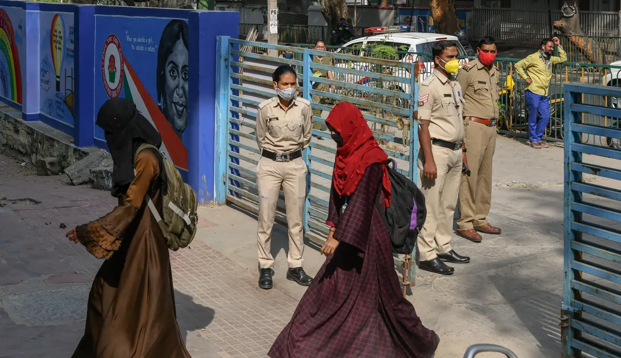 Polisi berjaga-jaga ketika siswa sekolah menengah negeri dan perguruan tinggi pra-universitas untuk wanita memasuki tempat institut pendidikan di Bangalore (16/2/2022). (AFP/Manjunath Kiran)