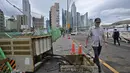 Seorang pria berjalan melewati kotak kontrol listrik yang rusak di jalan, setelah Topan Hinnamnor melewati Busan, Korea Selatan (6/9/2022). (AFP/Anthony Wallace)