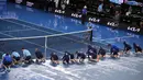 Para ball boy mengeringkan lapangan saat hujan menunda pertandingan perempat final kejuaraan tenis Australia Open 2023 di Melbourne, Selasa (24/1/2023). Setelah hujan berhenti, ball boy dan staf lapangan yang bertugas segera terjun ke lapangan bersama-sama mengeringkan lapangan. (AP Photo/Dita Alangkara)