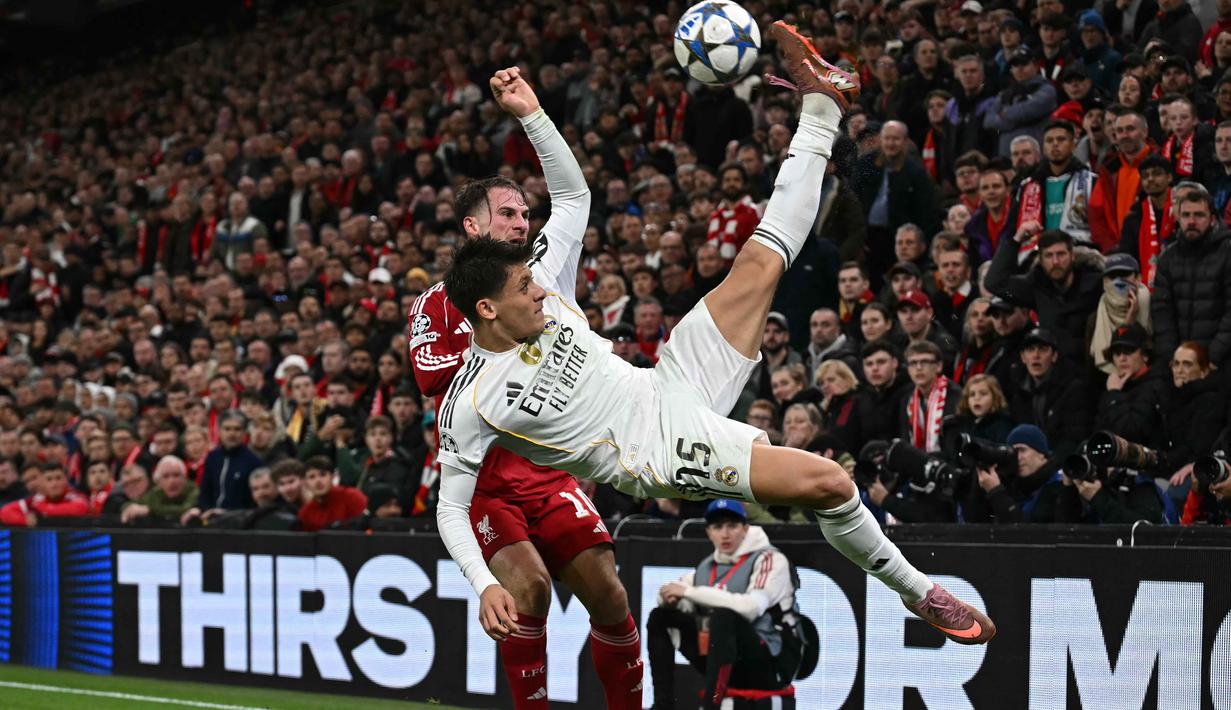 Gelandang Real Madrid asal Turki, Arda Guler (kanan) beradu dengan gelandang Liverpool asal Argentina, Alexis Mac Allister (kiri) dalam pertandingan pekan keempat Liga Champions 2025-2026 di Stadion Anfield, Inggris, pada Selasa 4 November 2025 waktu setempat atau Rabu (5/11/2025) dini hari WIB. Namun, upaya itu tetap tak membuahkan hasil. Hingga laga berakhir, skor 1-0 untuk Liverpool tak berubah. (Paul ELLIS/AFP)