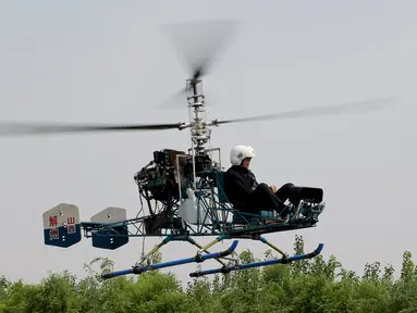 Pria 60 tahun bernama Guo Leiting saat terbang menggunakan helikopter buatannya sendiri di Yuncheng , provinsi Shanxi , Cina, 21 April 2016. Meskipun tinggal di desa dengan bahan seadanya, Ia mampu membuat helikopter. (REUTERS / Stringer)