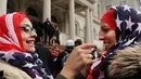 Seorang wanita membantu rekannya memakai kerudung bermotif bendera AS saat perayaan Hari Hijab Sedunia di depan Balai Kota, New York, Rabu (1/2). Hari Hijab Sedunia digagas oleh warga New York bernama Nazma Khan. (Spencer Platt / Getty Images / AFP)