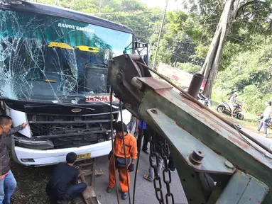 Petugas menggunakan mobil derek untuk mengevakuasi bus PO Merdeka yang menabrak pohon di jalur Lingkar, Jawa Barat, Sabtu (2/7). Kecelakaan terjadi karena rem bus bernopol Z 7829 T itu tidak berfungsi, alias blong. (Liputan6.com/Immanuel Antonius)