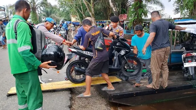 Personel Polres Pelalawan membantu warga mengangkat sepeda motor ke perahu motor untuk memperlancar mobilitas masyarakat.