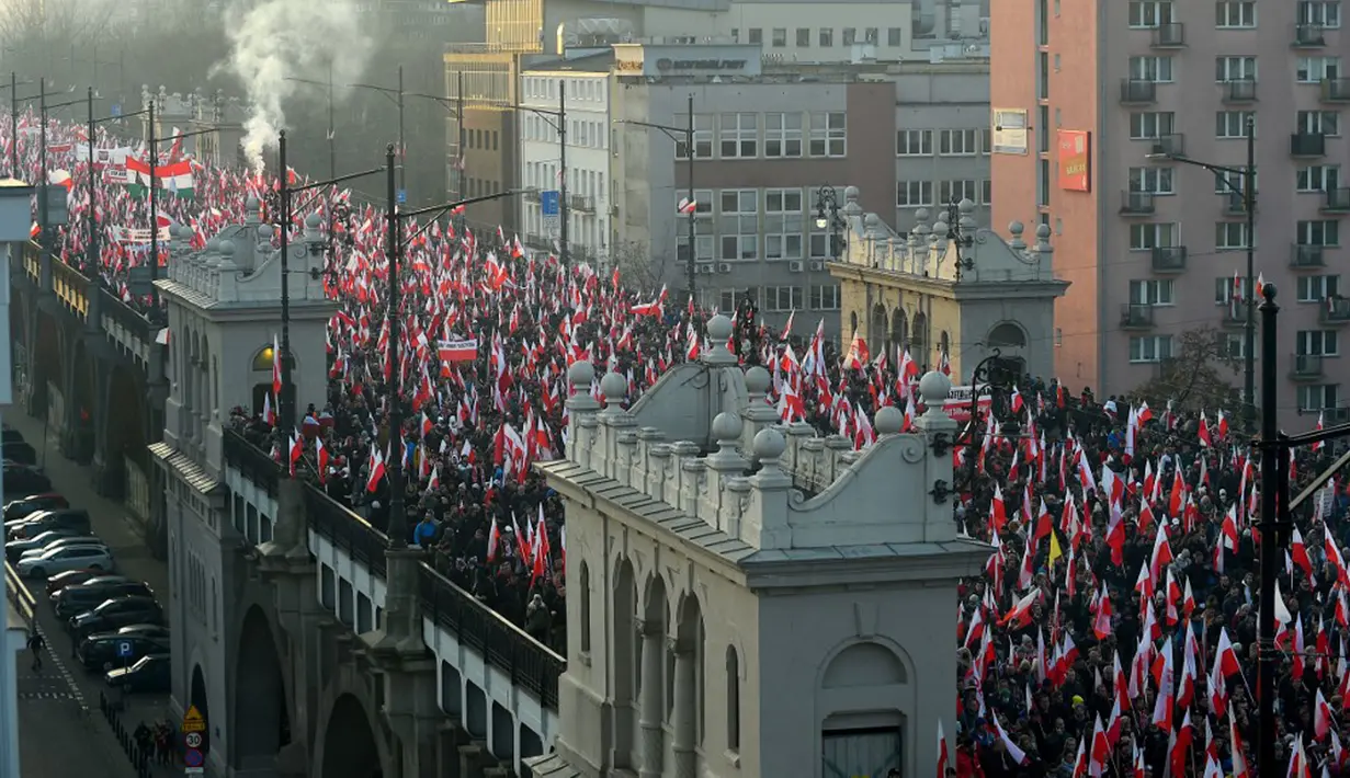 Orang-orang mengibarkan bendera nasional Polandia saat pawai untuk menandai Hari Kemerdekaan Nasional Polandia di Warsawa, Polandia, 11 November 2021. Hari Kemerdekaan Nasional Polandia dirayakan pada 11 November untuk memperingati ulang tahun Republik Polandia Kedua. (Adam Chelstowski/AFP)
