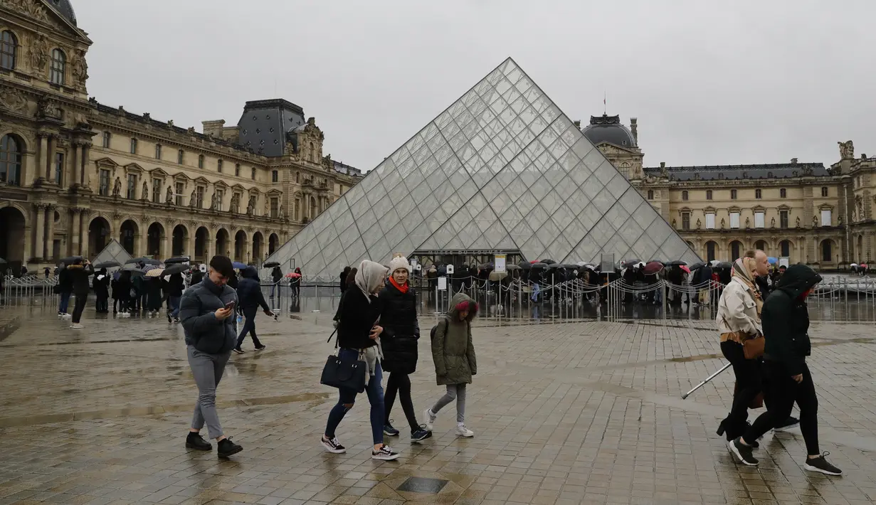 Orang-orang mengantre di depan Louvre Pyramide di Paris pada Minggu (1/3/2020). Louvre, museum yang paling banyak dikunjungi di dunia, ditutup sementara untuk pengunjung setelah para staf mengutarakan kecemasan dan ketakutannya tertular virus corona tipe baru, Covid-19. (Thomas SAMSON/AFP)