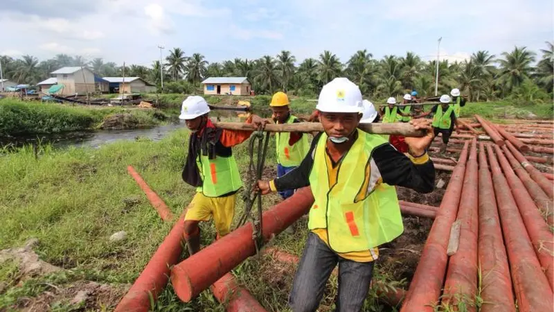 Karyawan PT PLN (Persero) bergotong-rotong mengangkat tiang yang akan digunakan untuk penyangga kabel listrik di Natuna, Kepulauan Riau. (Foto: Humas PLN)
