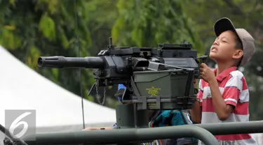 Seorang anak mencoba senjata ketika menaiki kendaraan tempur saat HUT Kopassus ke-64, Jakarta, (16/4). HUT mengangkat Tema Loyalitas, Moralitas dan Integritas demi mewujudkan Prajurit Hebat Profesional dan Dicintai Rakyat. (Liputan6.com/Helmi Afandi)