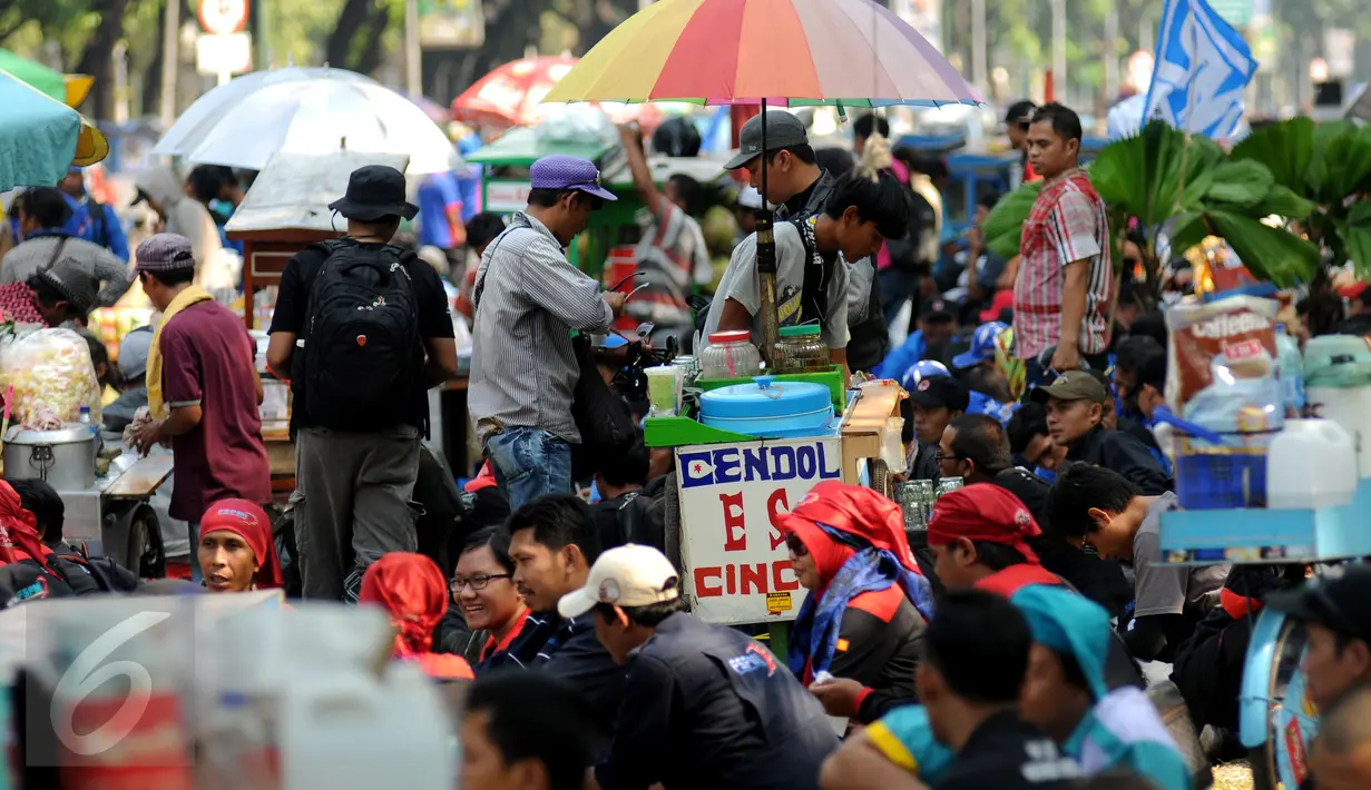 Pedagang kaki lima berdagang di ruas lajur bus Transjakarta di jalan Medan Merdeka Barat, Jakarta, Selasa (1/9/2015). Ribuan buruh dari berbagai elemen organisasi melakukan aksi di beberapa ruas jalan utama Jakarta. (Liputan6.com/Helmi Fithriansyah)