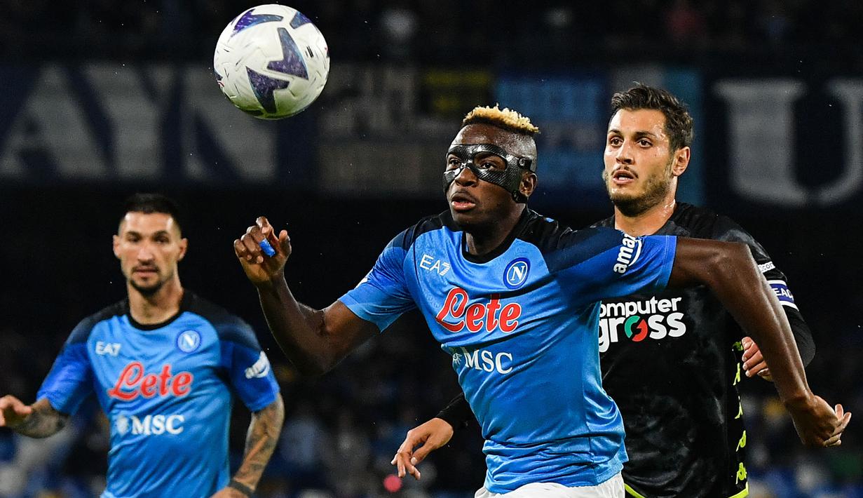 Pemain Napoli, Victor Osimhen (tengah) berusaha mengejar bola dibayangi pemain Empoli, Filippo Bandinelli pada laga lanjutan Liga Italia 2022/2023 di Diego Maradona stadium, Napoli, 8 November 2022. Osimhen tampil mengagumkan musim ini sebagai predator gol untuk Il Partenopei. Sejauh ini, ia telah mencetak 22 gol 5 assist dalam 27 pertandingan. Kini, pemain berkebangsaan Nigeria tersebut menjadi buruan klub-klub besar Eropa. (AFP/Tiziana Fabi)