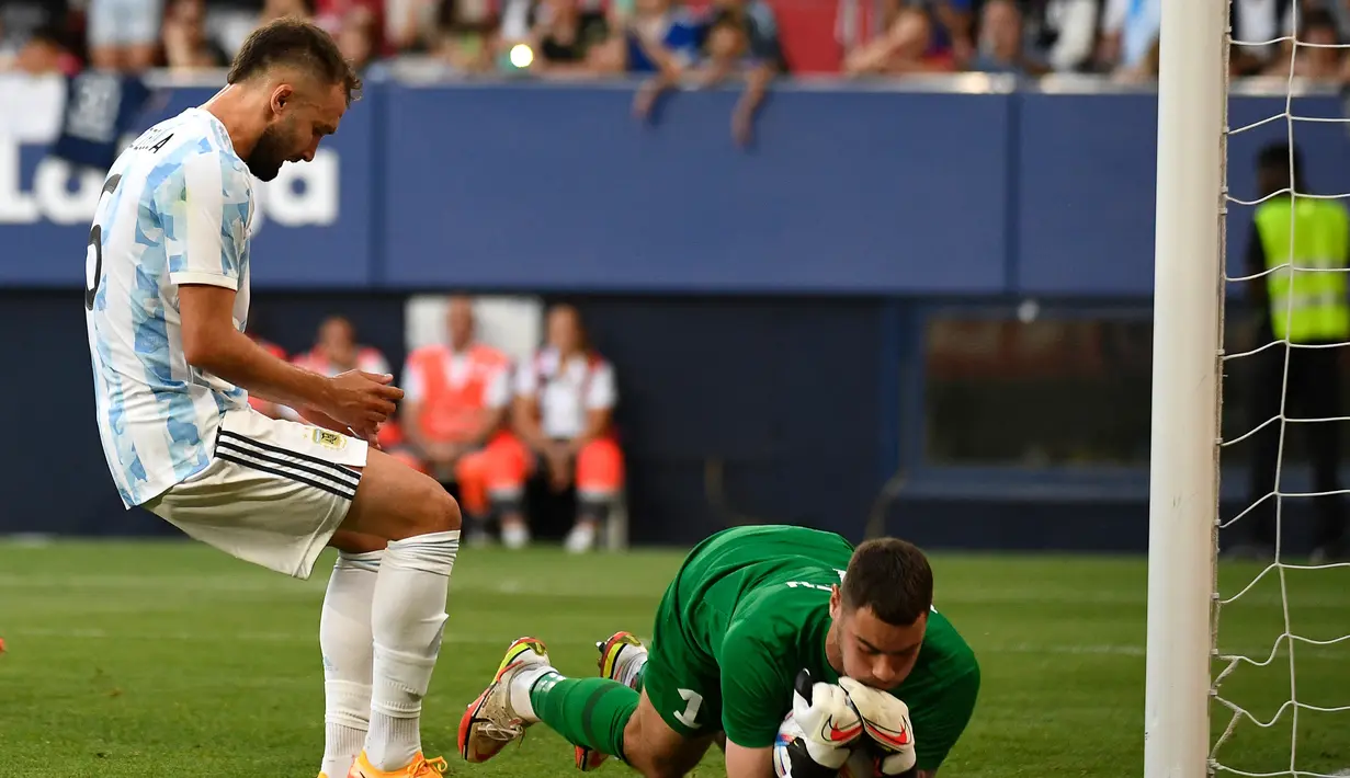 Kiper Estonia, Matvei Igonen menangkap bola dari kejaran pemain Argentina, Pezzella Jerman pada pertandingan persahabatan di stadion El Sadar di Pamplona, Spanyol utara, Senin (6/6/2022). Argentina menang besar atas Estonia 5-0. (AFP Photo/Ander Gillenea)