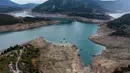 Foto ini menunjukkan sisa-sisa rumah yang muncul kembali ketika permukaan danau buatan Mornos menurun akibat kekeringan, di desa Kallio, sekitar 240 km barat laut Athena, Yunani pada 3 November 2025. Sebuah desa yang sudah tenggelam muncul kembali di Danau Mornos, Yunani pada 3 November 2025. (Angelos TZORTZINIS/AFP)