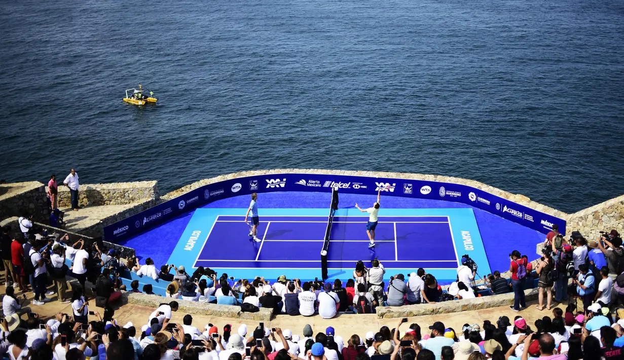 Petenis Austria Dominic Thiem (kanan) bertanding melawan petenis Jerman Alexander Zverev di forum "Sinfonia del Mar" di Acapulco, Meksiko (26/2). Yang menarik dari pertandingan ini, lapangan tenis berada di tebing pinggir pantai. (AFP Photo/Pedro Pardo)