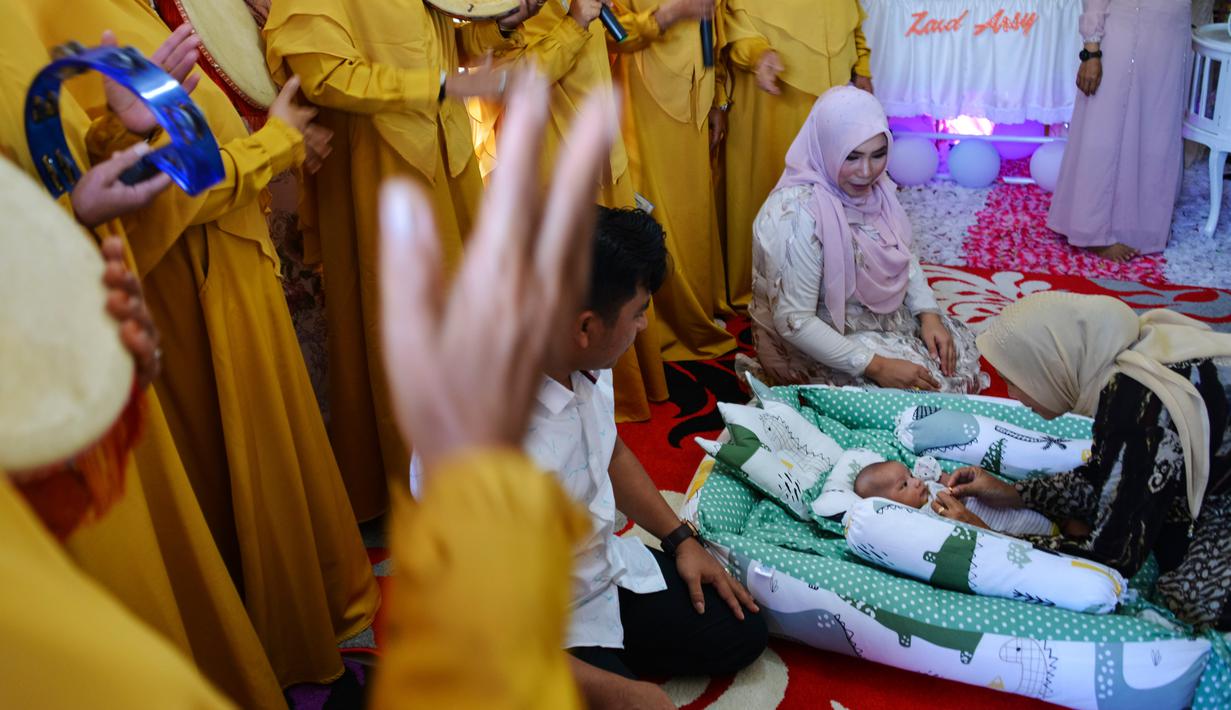 Seorang bayi menjalani ritual 'peutron tanoh aneuk' (turun tanah anak) di Banda Aceh, Aceh, Senin (15/7/2019). Ritual turun tanah anak telah menjadi tradisi sakral bagi masyarakat Aceh yang dilaksanakan pada saat bayi berusia 44 hari. (CHAIDEER MAHYUDDIN / AFP)