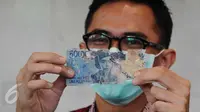 Petugas menunjukkan uang kertas rusak yang ditukarkan warga di Bank Indonesia, Jakarta, Selasa (26/1). BI menerapkan kebijakan untuk mengganti atau menukar uang tidak layak edar dengan uang yang layak edar (Liputan6.com/Angga Yuniar)