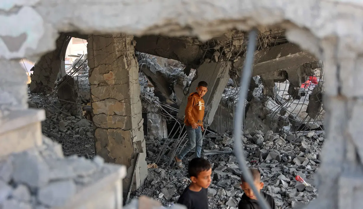 Sedikitnya 27 warga Palestina tewas dan puluhan lainnya terluka, beberapa korban luka berada dalam kondisi kritis. Tampak dalam foto, anak-anak Palestina berjalan di antara puing-puing bangunan yang rusak milik Kementerian Wakaf Agama, yang digunakan sebagai tempat penampungan bagi pengungsi di kawasan Zeitoun, Kota Gaza, pada Kamis 20 November 2025, sehari setelah bangunan tersebut menjadi sasaran serangan militer Israel. (Omar AL-QATTAA /AFP)