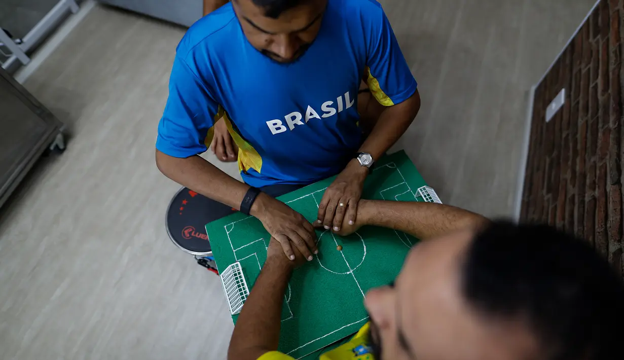 Helio Fonseca (kanan) membantu temannya yang tuli dan buta Carlos Junior saat pertandingan sepak bola Grup G Piala Dunia antara Brasil dan Swiss di Osasco, Sao Paulo, Brasil, 28 November 2022. Fonseca menggunakan meja taktil dan sentuhan pada tubuh tunanetra dan tunarungu untuk menunjukkan kepada mereka pergerakan bola dan para pemain selama pertandingan sepak bola. (AP Photo/Marcelo Chello)
