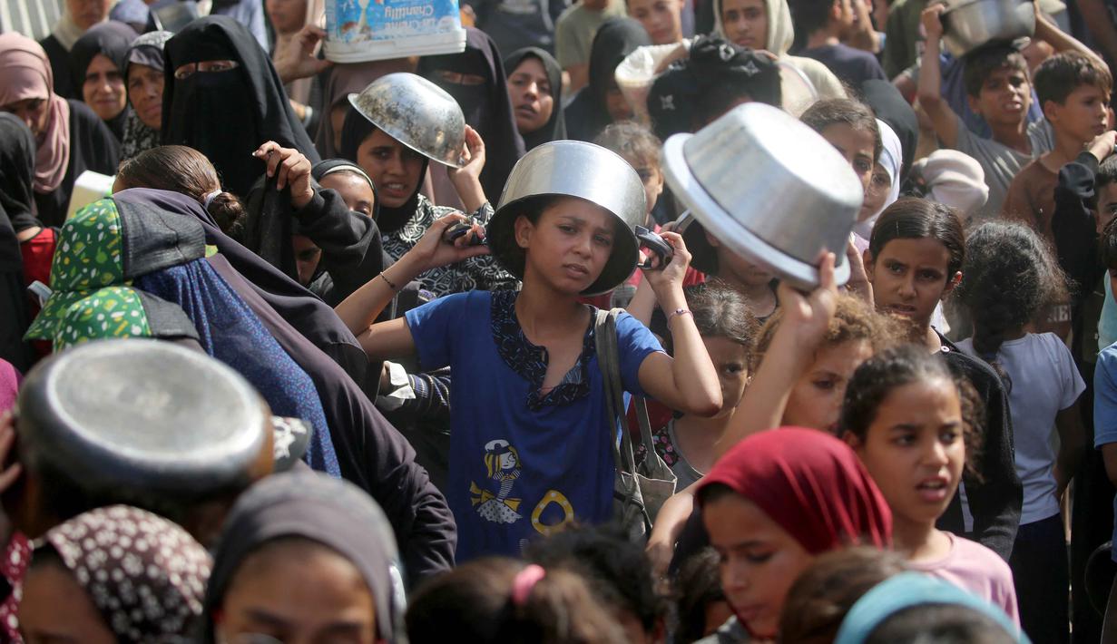 Seorang anak laki-laki Palestina yang sedang menunggu dengan pancinya untuk menerima seporsi makanan, di sebuah tempat penampungan yang telah dihuni banyak keluarga, di Nuseirat, pusat Jalur Gaza, pada 2 November 2025. Di sisi lain, PBB terus menyalurkan bantuan kemanusiaan di seluruh Gaza meski wilayah tersebut beberapa kembali diguncang serangan udara Israel. (EYAD BABA/AFP)
