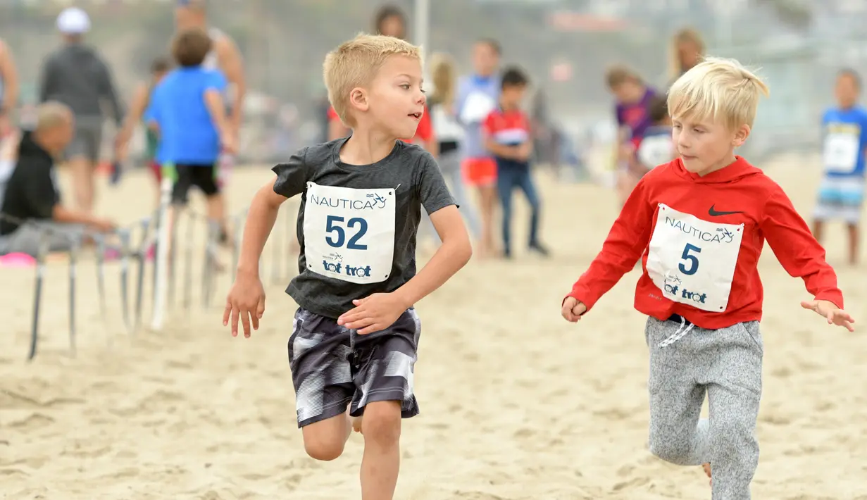 Ekspresi dua anak saat berpartisipasi dalam 'Tot Trot' selama Nautica Malibu Triathlon di Pantai Zuma di Malibu, California (14/9). (Noel Vasquez / Getty Images untuk Nautica / AFP)