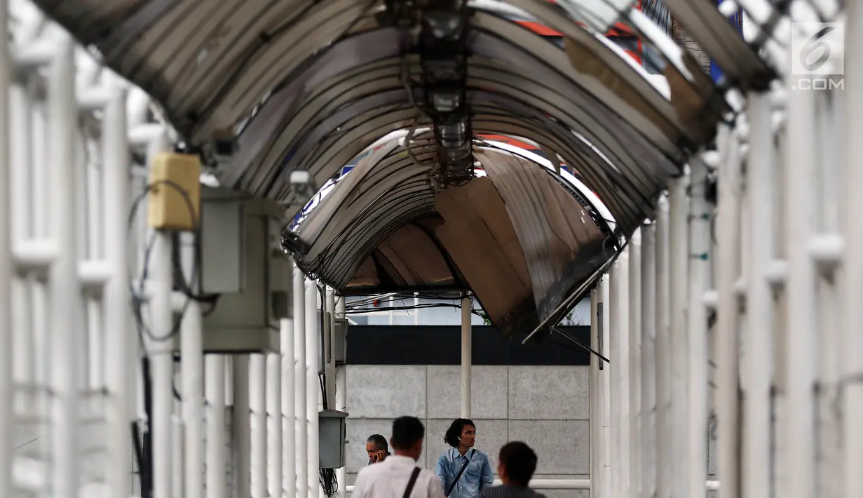 Warga melintasi Jembatan Penyeberangan Orang (JPO) yang rusak di kawasan Dukuh Atas, Jakarta, Rabu (12/12). Hingga saat ini, JPO Dukuh Atas yang rusak belum juga diperbaiki. (Liputan6.com/JohanTallo)